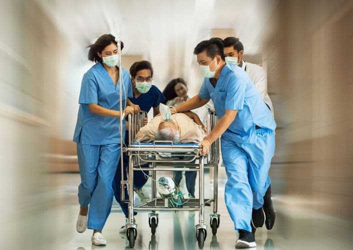 Healthcare team rushing patient on gurney through hospital corridor